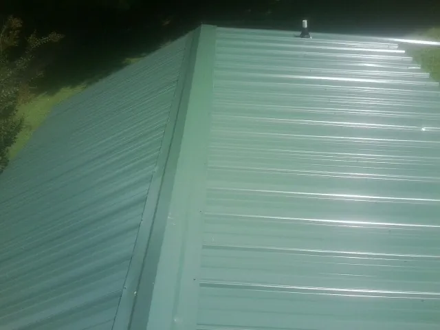 New green metal panels meeting at the ridge of a roof — Flat Roof Repair work by our crew in Easton