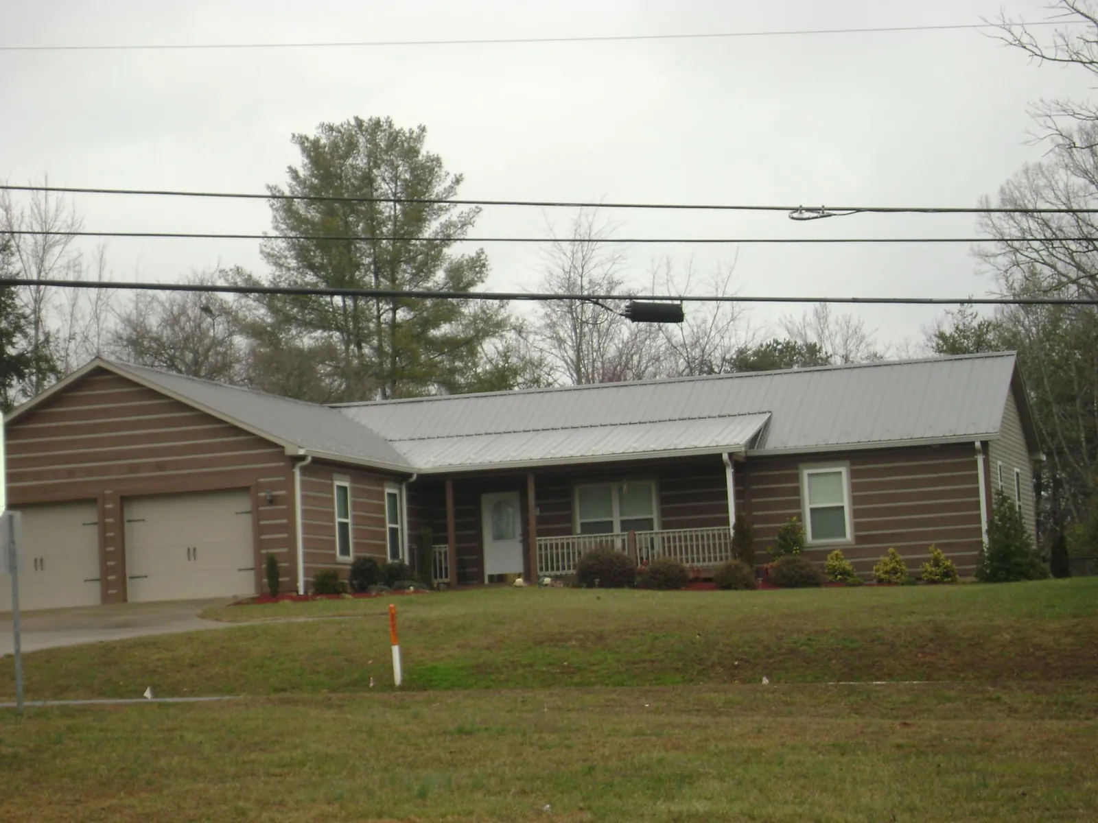 Gray metal roof on a log sided ranch home with a front porch in Easton
